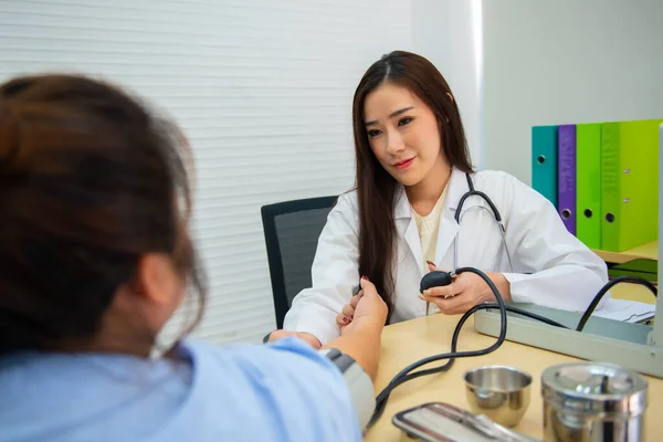 stock image Asian female doctor use mercury blood pressure to determine patient blood pressure.