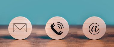 Müşteri hizmetleri ile iletişim kurun Posta, e-posta, telefon simgeleri masanın üzerine yerleştirilen ahşap çember üzerinde.