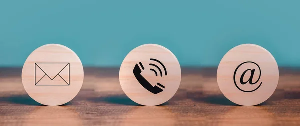 Müşteri hizmetleri ile iletişim kurun Posta, e-posta, telefon simgeleri masanın üzerine yerleştirilen ahşap çember üzerinde.