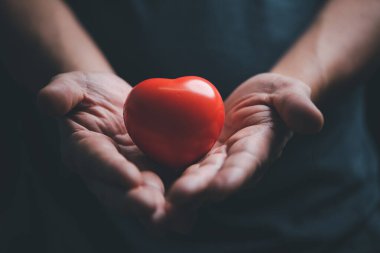 Aşk, sağlık, organ bağışı, dünya kalp günü, dünya sağlık günü, farkındalık, refah, aile sigortası konsepti için el ele tutuşmak ve kırmızı kalp vermek.