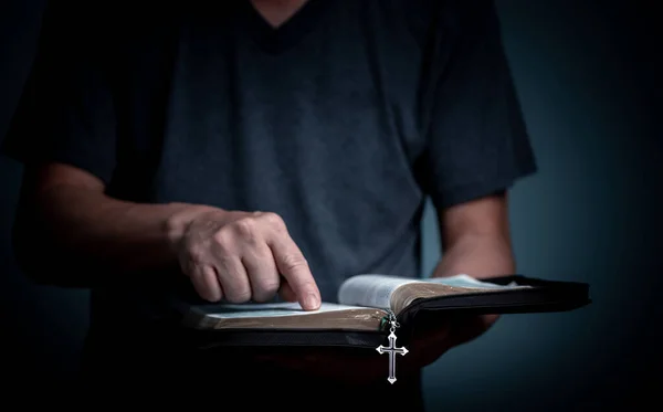 聖書を読んで 本のフォントでクロスネックレスで単語を指している若い男 — ストック写真