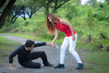 Genç bir kadın parkta koşan bir adama yardım ediyor..