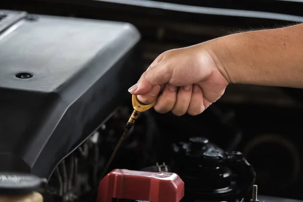 Man hand pulling oil gauge stick up for checking level of motor oil lubricant in the engine, car maintenance service concept.