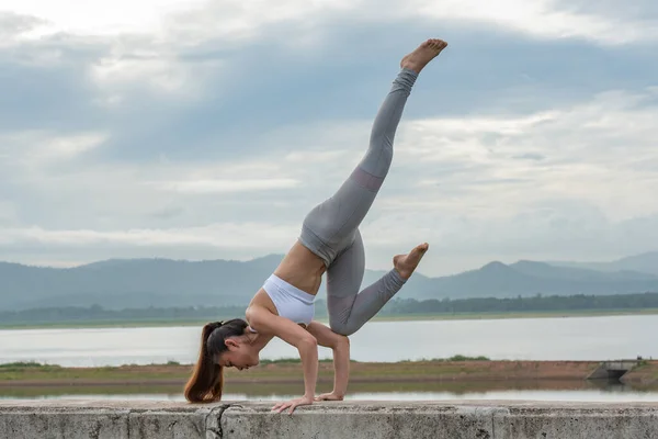 Genç Asyalı bir kadın, sabah dağda güzel bir gölde yoga yapıyor..