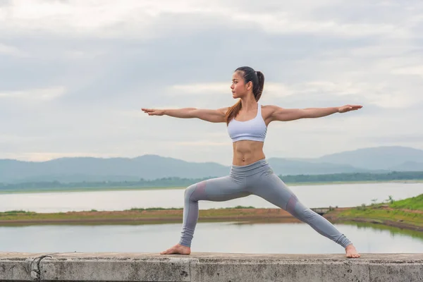 Genç Asyalı bir kadın, sabah dağda güzel bir gölde yoga yapıyor..