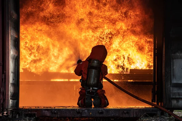 stock image Firefighter Rescue training to stop burning flame, Fireman wear hard hat and safety uniform suit for protection burn using hose with chemical water foam spray.