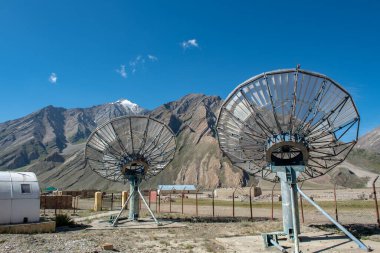 Kırsal alanda iletişim uydu antenleri ağ teknolojisi dağ ve mavi gökyüzü arkaplanı aralığında.