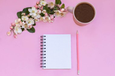 Notlar için bir defter pembe arka planda, kalem, hesap makinesi, kahve ve çiçeklerin yanında yatar. Kişisel bütçe planlama. Kişisel Yönetim. 