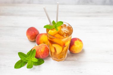 Şeftalili buzlu çay, beyaz ahşap masada nane şekeri. Yazın ferahlatıcı bir içecek.. 