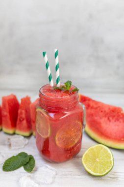 Dilimlenmiş meyve, nane ve limon yapraklı karpuz içecekleri beyaz ahşap arka planda. Yazın ferahlatıcı bir içecek.. 