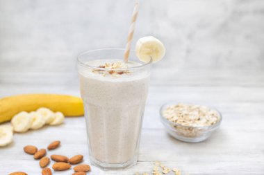 Yulaf ezmeli muzlu smoothie ve camlı badem. Sağlıklı yiyecekler. Beyaz ahşap arka plan. Uzayı kopyala Diyet yemek.. 