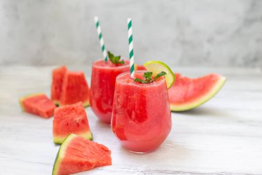 Dilimlenmiş meyve, nane ve limon yapraklı karpuz içecekleri beyaz ahşap arka planda. Yazın ferahlatıcı bir içecek.. 