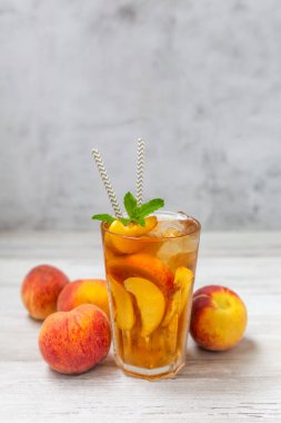 Şeftalili buzlu çay, beyaz ahşap masada nane şekeri. Yazın ferahlatıcı bir içecek.. 