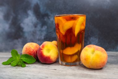 Şeftalili buzlu çay, beyaz ahşap masada nane şekeri. Siyah arka plan. Yazın ferahlatıcı bir içecek.. 