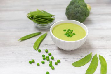 Beyaz ahşap masada yeşil bezelyeli krema çorbası. Sağlıklı, diyet yiyecekler. Vejetaryen yemeği. Beslenme yemeği. 