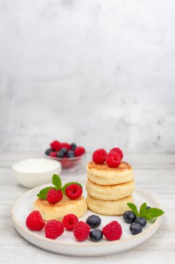 Süzme peynirli krep ya da taze ahududu ve böğürtlenli şerbetli beyaz ahşap masa. Tatlı kahvaltı ya da öğle yemeği, lezzetli tatlı. 