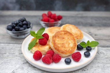 Süzme peynirli krep ya da taze ahududu ve böğürtlenli şerbetli beyaz ahşap masa. Tatlı kahvaltı ya da öğle yemeği, lezzetli tatlı. 