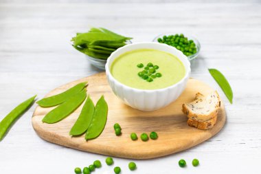 Beyaz ahşap masada yeşil bezelyeli krema çorbası. Sağlıklı, diyet yiyecekler. Vejetaryen yemeği. Beslenme yemeği. 