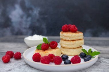 Süzme peynirli krep ya da taze ahududu ve böğürtlenli şerbetli beyaz ahşap masa. Tatlı kahvaltı ya da öğle yemeği, lezzetli tatlı. 