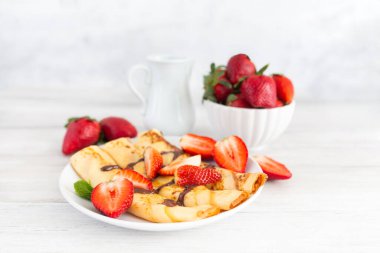 İnce krepler, çilekli Fransız krepleri ve çikolata sosu. Yakından bak. Tatlı tatlı kahvaltı, öğle yemeği ya da tatlı.