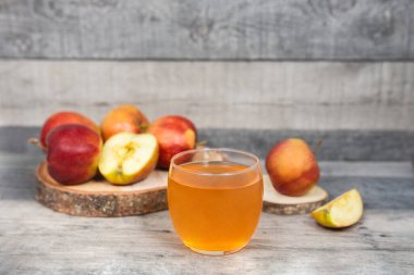 Ahşap masada bir bardak elma suyu ve elma dilimi. Vitaminli sağlıklı içecek.. 