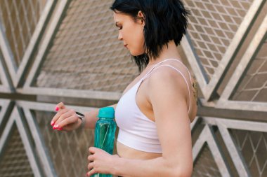 Antrenman, hidrasyon ve sporcu kadın koşu sırasında dışarıda su içme, spor egzersizi. Şehir merkezinde kadın sporcu eğitimi almış.. 