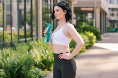 Spor, hidrasyon ve spor yapan bir kadın koşu ve spor yaparken şehrin dışında su içiyor. Spor konsepti. 