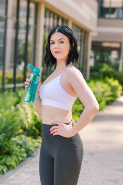 Spor, hidrasyon ve spor yapan bir kadın koşu ve spor yaparken şehrin dışında su içiyor. Spor konsepti. 