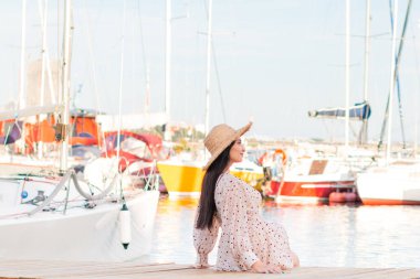 Genç turist kadınlar, yat limanında yürürken mutlu olurlar. Bir kadın deniz kenarında tatilin tadını çıkarır. Kulübesi olan güzel kadınlar.. 