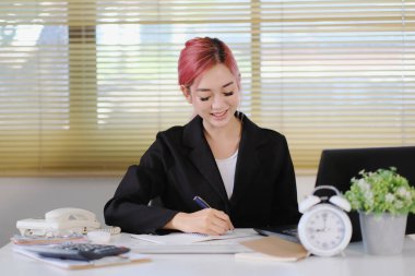 Ofiste çalışan Asyalı iş kadını dizüstü bilgisayar kullanıyor.