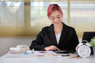 Ofiste hesap makinesi kullanan Asyalı iş kadını