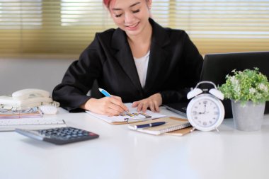 Dizüstü bilgisayarla çalışan iş kadını ve ofiste belgeler.