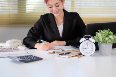 Dizüstü bilgisayarla çalışan iş kadını ve ofiste belgeler.