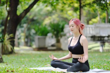 Parkta yoga yapan Asyalı güzel kadın. 