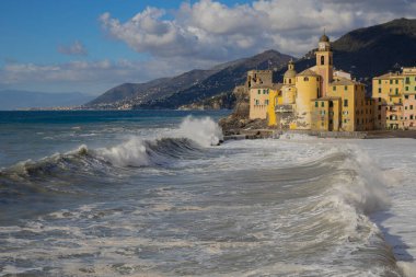 Rough sea on the beach of Camogli and the Basilica of Santa Maria Assunta,  Genoa province, Italy. clipart