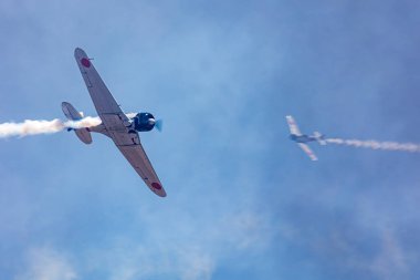 Japanese zero flying in smoke at airshow with a second plane in smoke clipart