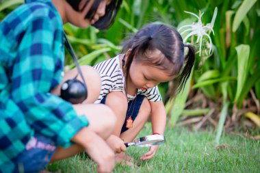 Asyalı küçük kız parkta oynamak için büyüteç kullanıyor. STKHome