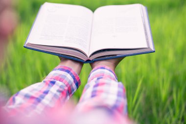 Yeşil çimenlerin üzerinde uzanan mutlu kadın parkta kitap okuyor (açık havada) SSTKHome