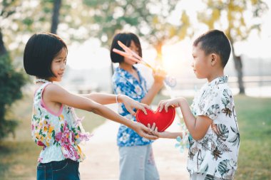 Sevgililer gününde kırmızı kalp şeklinde bir oyuncak tutan mutlu küçük kız.