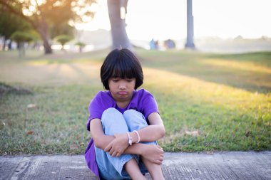 Dışarıda yalnız oturan üzgün küçük bir kız.