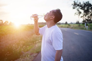 Su şişeli adam dışarıda egzersiz molası veriyor.