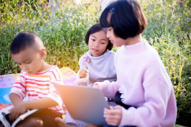 Çocuklar büyüteçle ormanda keşfe çıkıyorlar.