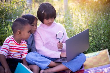 Çocuklar büyüteçle ormanda keşfe çıkıyorlar.