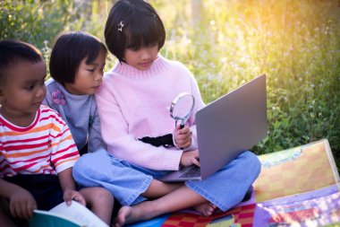 Çocuklar büyüteçle ormanda keşfe çıkıyorlar.