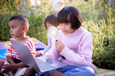 Çocuklar büyüteçle ormanda keşfe çıkıyorlar.