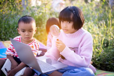 Çocuklar büyüteçle ormanda keşfe çıkıyorlar.