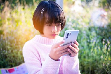 Sevimli küçük kız akıllı telefon kullanıyor. arka planda çim. Kız üzerinde bir balkabağı ile bir saç tokası