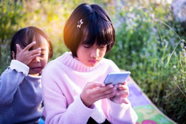 Sevimli küçük kız akıllı telefon kullanıyor. arka planda çim. Kız üzerinde bir balkabağı ile bir saç tokası