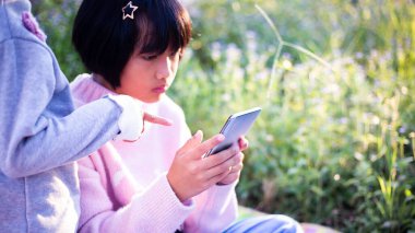 Sevimli küçük kız akıllı telefon kullanıyor. arka planda çim. Kız üzerinde bir balkabağı ile bir saç tokası