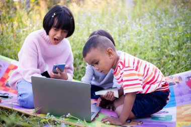 Çocuklar büyüteçle ormanda keşfe çıkıyorlar.